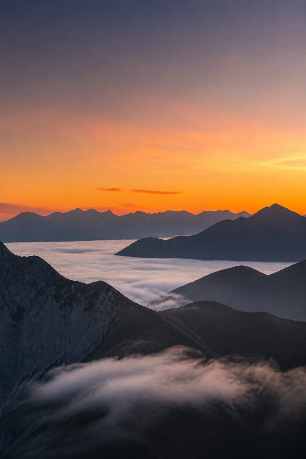 AI-generated alpine peaks above a sea of clouds at sunset